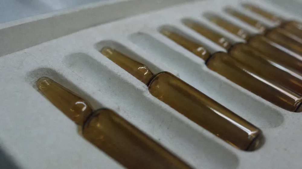 Several small amber glass ampoules resting in a foam-lined tray, photographed close up in cool light, with the deeper rows of the tray out of focus.
