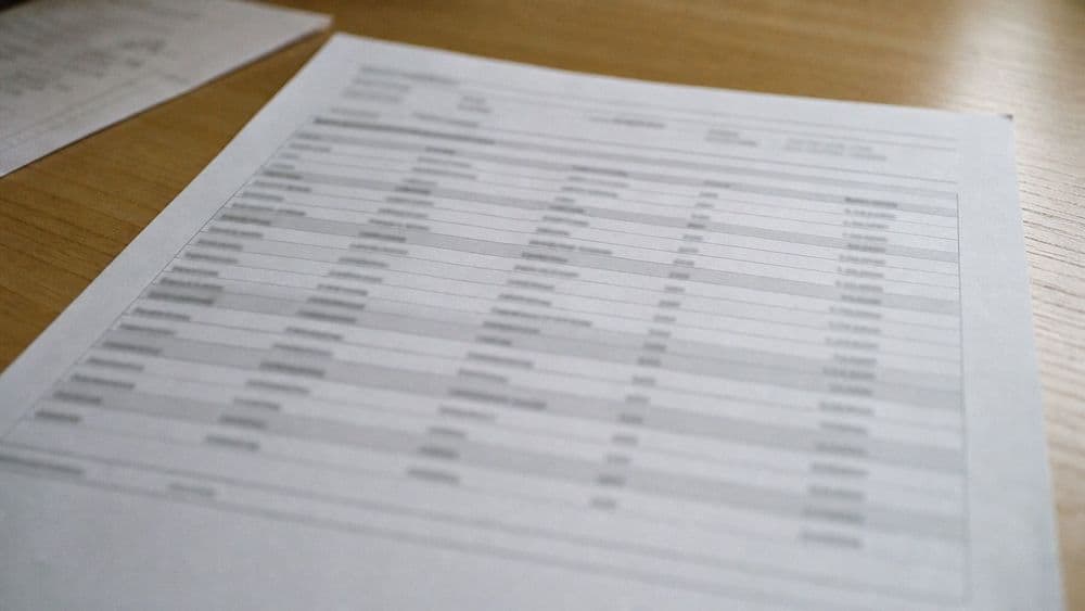 Close crop of a printed laboratory potency report on a plain desk, the rows and columns readable as structure but the text out of focus.